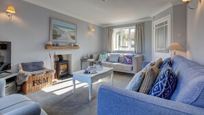 A living room with a sofa, a coffee table, a fireplace, and a window with curtains. - Tern Cottage (Holme-next-the-Sea), Norfolk (Holme-next-the-Sea)