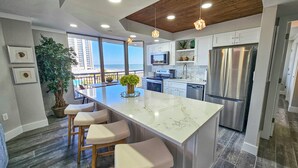 A modern kitchen with a large island, stainless steel appliances, and a view of the ocean. - Superbly updated ocean view condo, 303 Brighton, full access (Myrtle Beach)