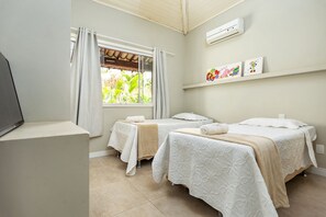 Una habitación con dos camas, televisión y ventana con cortinas.