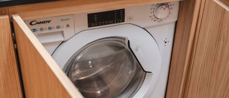 A Candy Smart washing machine in a wooden cabinet.