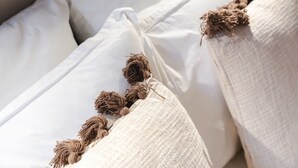 A close-up of a bed with white pillows and a beige blanket. - AC Apartment With Terrace in the Center of Paris (Paris)