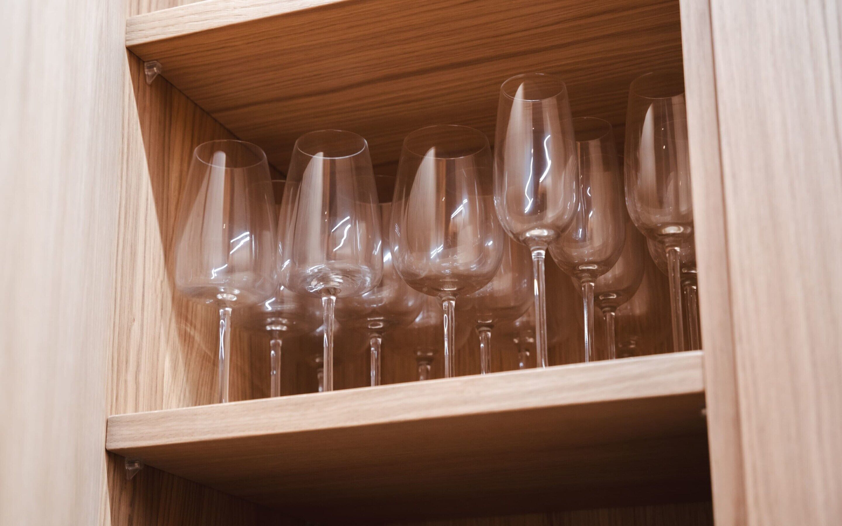 A wooden cabinet with multiple wine glasses neatly arranged inside.