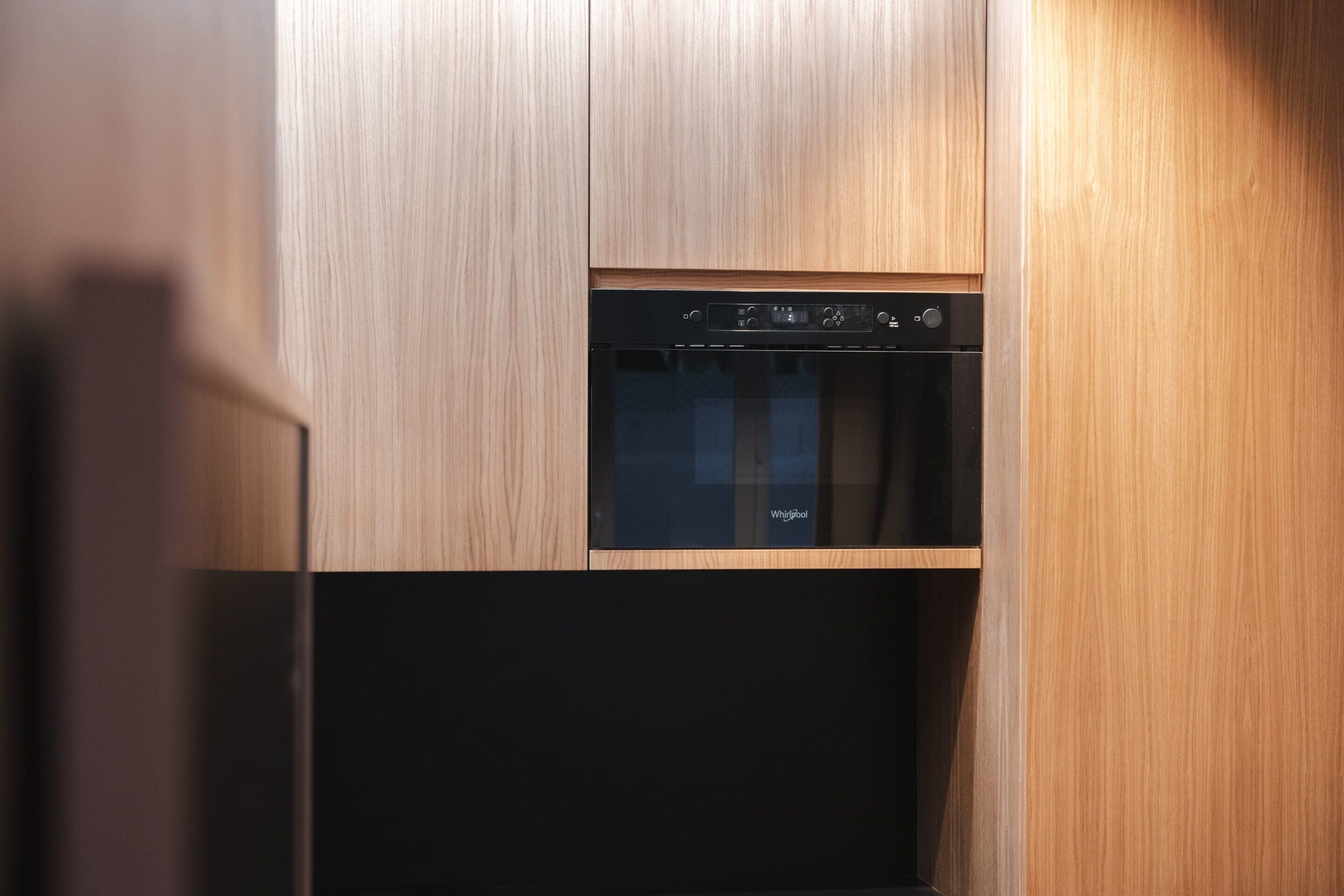 A modern kitchen with a built-in dishwasher and oven, featuring a sleek, wooden finish.