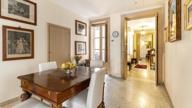 A dining area with a wooden table and white chairs, framed artwork on the walls, and a clock. - From the Baron and Baroness, charm and art's house with terrace (Palermo)