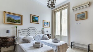 A hotel room with two beds, a wooden headboard, a nightstand, a lamp, and framed pictures on the wall. - From the Baron and Baroness, charm and art's house with terrace (Palermo)