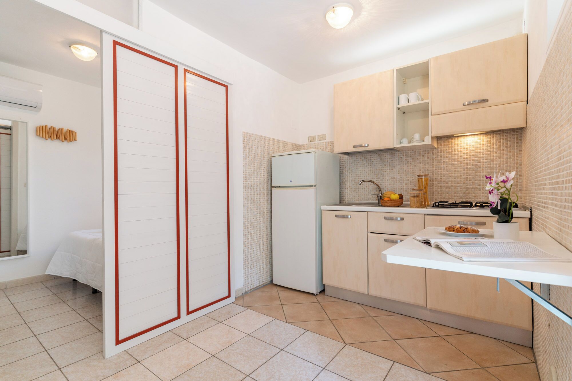 Una cocina moderna con refrigerador, estufa y alacenas blancas.