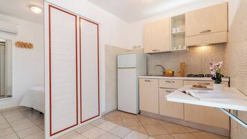 Una cocina moderna con refrigerador, estufa y alacenas blancas.