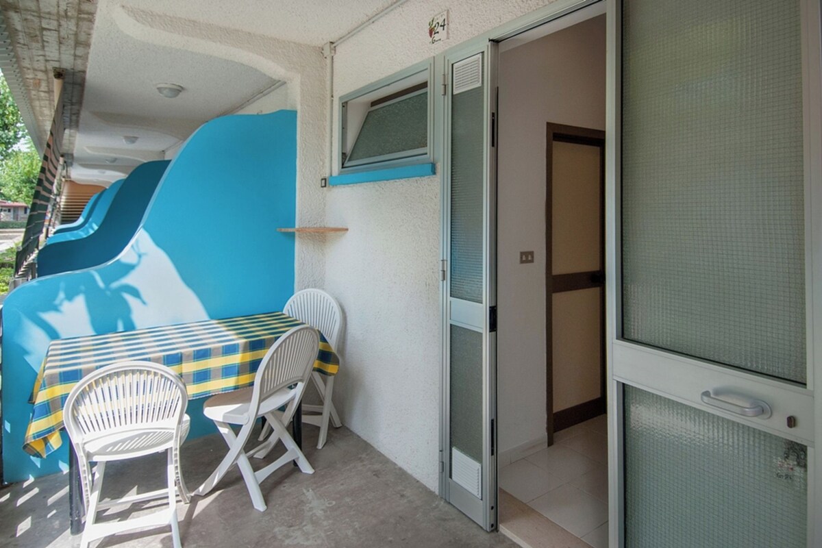 Een kamer met een blauwe wand, een tafel met een geruit tafelkleed en twee witte stoelen.