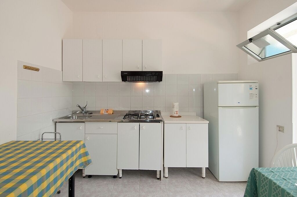Een compacte kitchenette met een gasfornuis, een spoelbak en een witte koelkast.
