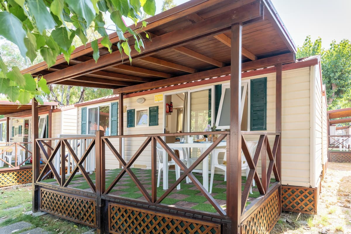 A covered outdoor area with a wooden deck, white plastic chairs, and a table.