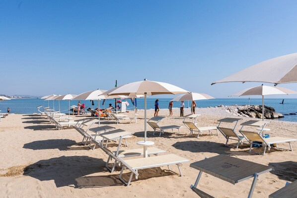 A beach with sun loungers and umbrellas, a clear sky, and the sea in the background. - Club del Sole Roseto degli Abruzzi Easy Camping Village (Roseto degli Abruzzi)