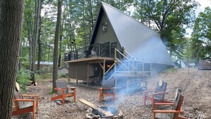 Eine Hütte mit geneigtem Dach, Sitzgelegenheit im Freien und einem Feuerkorb.