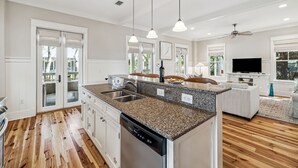 A modern kitchen with granite countertops, a dishwasher, and pendant lighting.