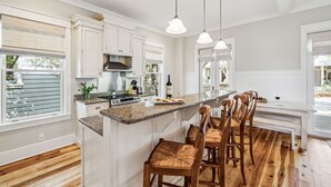 A kitchen with white cabinetry, a granite countertop, and a wooden bar stool seating area.