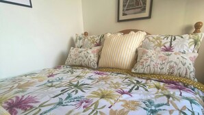 A bed with floral-patterned bedding, a framed picture on the wall, and a wooden headboard. - R and B Warm and Cosy Cabin (Londonderry)