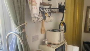 A compact kitchen with a wooden cutting board, a microwave, a toaster, and a kettle. - R and B Warm and Cosy Cabin (Londonderry)