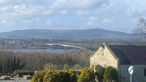 A stone building with a traditional roof, a no entry sign, and a view of a bridge over a river with hills in the background. - R and B Warm and Cosy Cabin (Londonderry)
