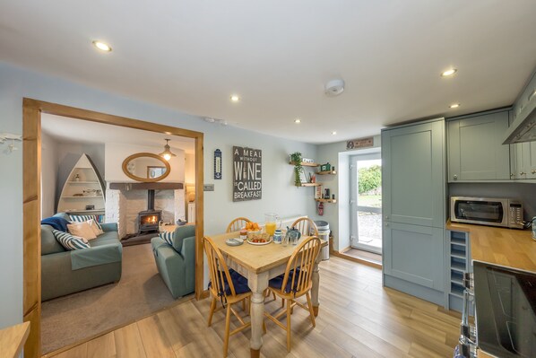 A modern kitchen with light blue cabinets, a dining area with a wooden table and chairs, and a cozy living space with a sofa and a fireplace.
