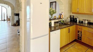Una cocina con un refrigerador blanco, armarios de madera, lavavajillas y piso de baldosas.