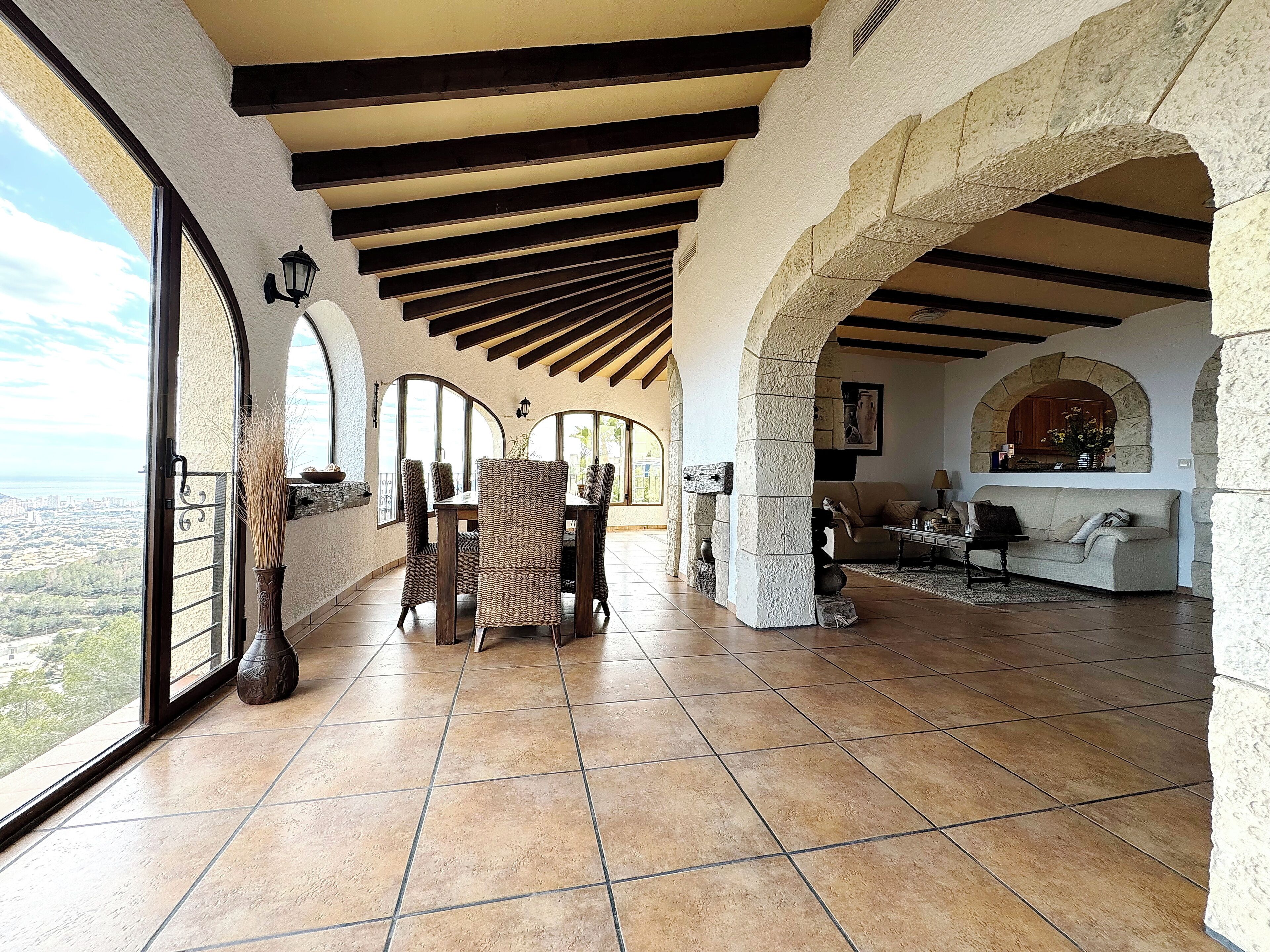 A spacious living area with a high ceiling, stone arches, and a view of the city.