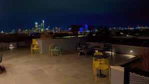 An outdoor seating area with chairs and tables, a city skyline in the background, and a view of the city at night. - Studio Apartment in the Heart of Philadelphia. (Philadelphia)