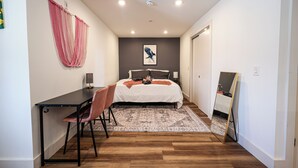 A bedroom with a bed, a desk, a chair, a rug, and a mirror. - Studio Apartment in the Heart of Philadelphia. (Philadelphia)