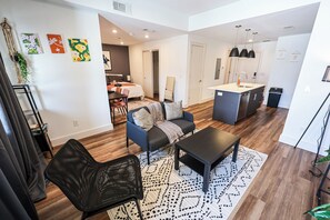 A modern living room with a sofa, a coffee table, and a black chair. There is a dining area with a table and chairs in the background. - Studio Apartment in the Heart of Philadelphia. (Philadelphia)