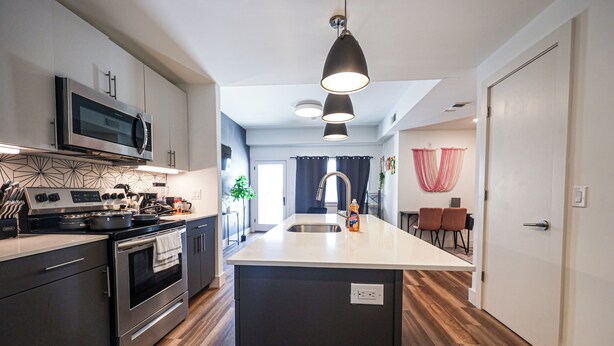 A modern kitchen with stainless steel appliances, a central island with a sink, and a dining area with chairs. - Studio Apartment in the Heart of Philadelphia. (Philadelphia)