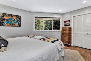 Quarto com cama, janela, guarda-roupa e um quadro na parede.