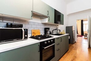 A modern kitchen with a microwave, stove, and oven, light green cabinets, and a white countertop.