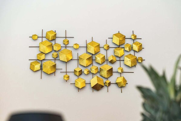 A wall with a geometric pattern of gold cubes and rods.