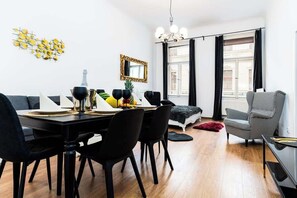 Uma sala de jantar moderna com mesa e cadeiras pretas, um objeto decorativo na parede e uma poltrona xadrez.