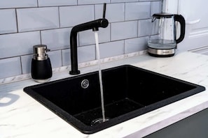 A kitchen sink with a black faucet and a coffee maker on the counter.