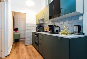 Uma cozinha moderna com armários cinzentos, bancada branca e piso de madeira.