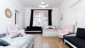 A bedroom with a bed, two chairs, a sofa, a window with curtains, a chandelier, and a mirror on the wall. - Victory King's Residence (Prague)