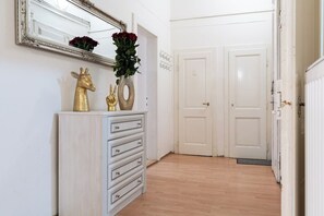 Un pasillo con un aparador blanco, un espejo y un florero con flores rojas.