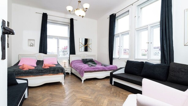 A bedroom with two beds, a sofa, and large windows. - Victory King's Residence (Prague)