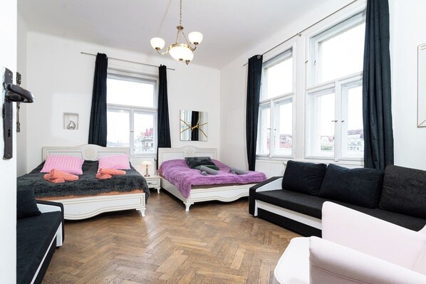A bedroom with two beds, a sofa, and large windows.