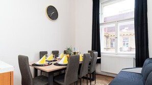 A dining area with a wooden table, grey chairs, and a clock on the wall. - Victory King's Residence (Prague)