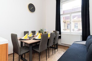 A dining area with a wooden table, grey chairs, and a clock on the wall.