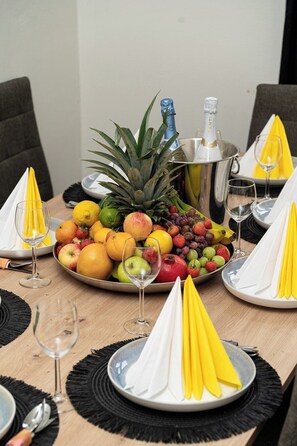Una mesa de comedor con una bandeja de frutas, copas de vino y una botella de champán.