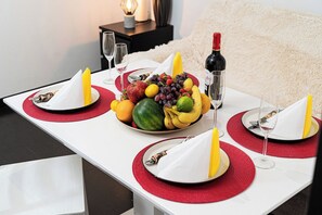 A dining table set with plates, cutlery, and a fruit bowl.