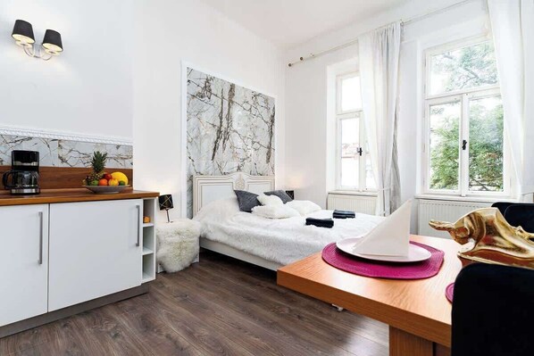A modern bedroom with a bed, a desk, and a window.