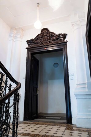 A grand entrance with an ornate black door, white columns, and a patterned floor.