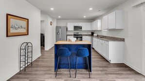 A modern kitchen with white cabinets, a central island with bar stools, and a microwave above the island. - Quiet Retreat Perfect for Families 5 Bedroom Home (Rocky Mount)