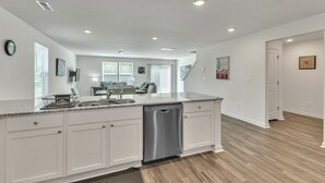 A modern kitchen with white cabinetry, a stainless steel dishwasher, and a granite countertop. - 5br Retreat With Garage Parking 5 Bedroom Home (Rocky Mount)