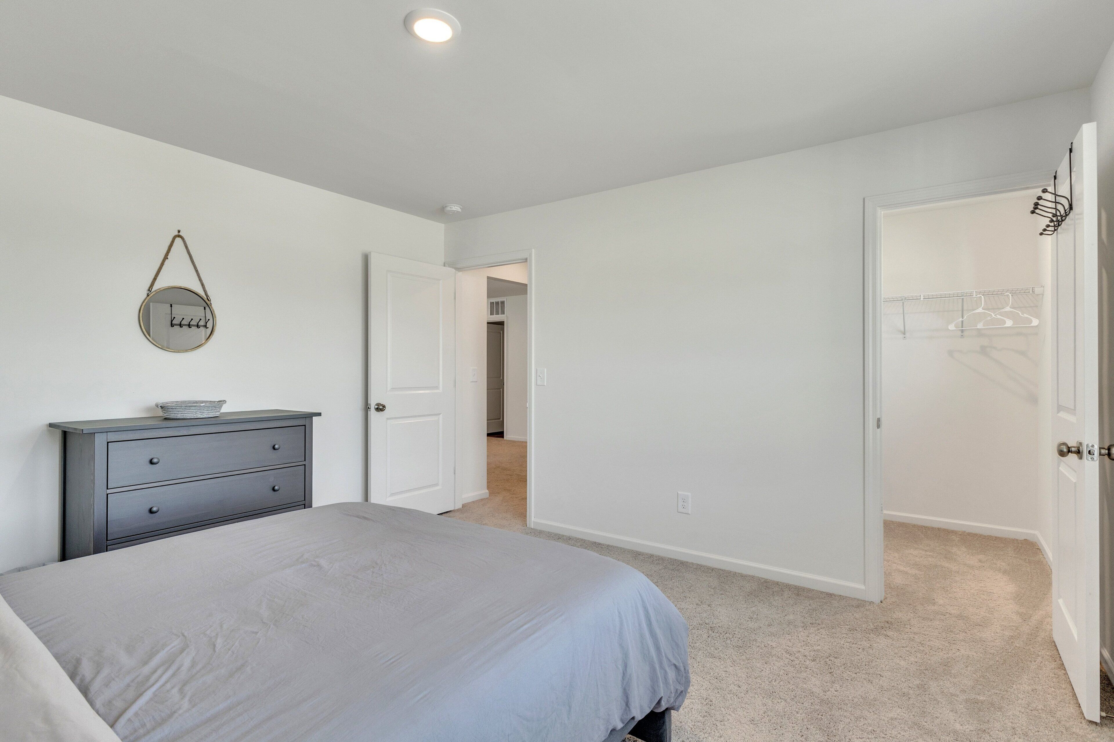 A bedroom with a bed, a dresser, and a door leading to a closet.