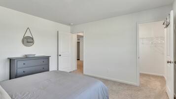 A bedroom with a bed, a dresser, and a door leading to a closet.