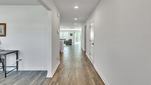 A hallway with a wooden floor, white walls, and a dining area with a table and chairs. - 5br Retreat With Garage Parking 5 Bedroom Home (Rocky Mount)