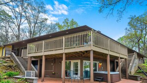 A two-story house with a covered patio, outdoor seating, and a hot tub.